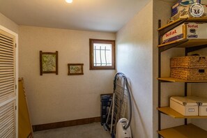 A laundry room with a ceiling fan, ironing board, and shelves with boxes and baskets. - Androsace - VAL CENIS (VAL CENIS)