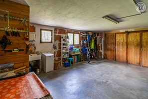 A room with a concrete floor, wooden cabinets, a bicycle, and a window with a view.
