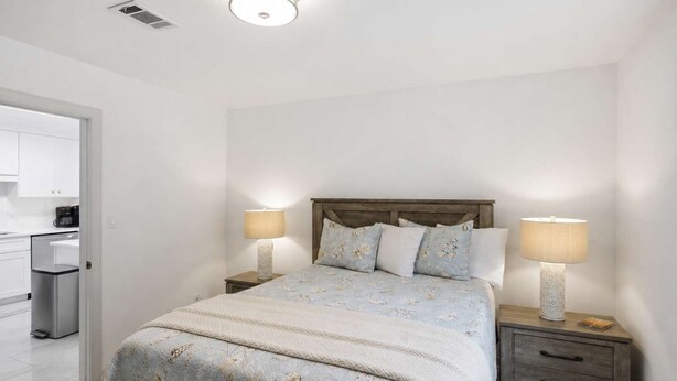 A bedroom with a bed, two bedside tables with lamps, a wooden headboard, and a white door leading to a bathroom. - New- Eastpoint- Next to RV park- Pet Friendly (Eastpoint)