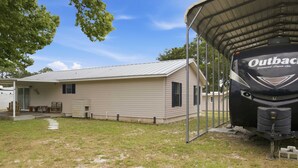A mobile home with a covered outdoor area, a small porch, and a recreational vehicle parked nearby. - New- Eastpoint- Next to RV park- Pet Friendly (Eastpoint)