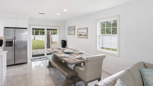 A modern kitchen with a built-in refrigerator, a dining table set for four, and a view of the backyard through a sliding glass door. - New- Eastpoint- Next to RV park- Pet Friendly (Eastpoint)