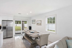 A modern kitchen with a built-in refrigerator, a dining table set for four, and a view of the backyard through a sliding glass door. - New- Eastpoint- Next to RV park- Pet Friendly (Eastpoint)