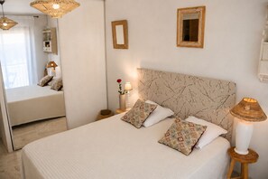 A bedroom with a large bed, two bedside lamps, a mirror, and a bedside table with a vase and a candle. - Two-room apartment with a terrace and a view of the Port of Nice—everything is within walking distance! (Nice)