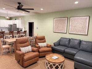 A living room with a grey sofa, brown leather chairs, a wooden coffee table, and a ceiling fan. - The Lou | Walk 2 Beach, Golf Cart & Beach Toys! (Gulf Shores)