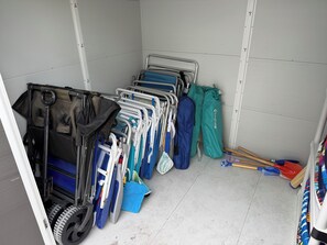 Ein Lagerbereich mit verschiedenen Gegenständen, darunter ein Kinderwagen, eine blaue Tasche und eine grüne Hose.