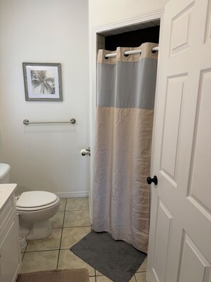 Ein Badezimmer mit Toilette, Handtuchhalter, Duschvorhang und einem Bild an der Wand.