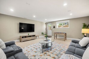 Una sala de estar con televisor de pantalla plana, sofá, mesa de centro y mesa de fútbol.