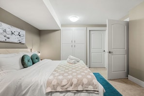 Un dormitorio con cama, mesita de noche, lámpara de pared y una puerta.