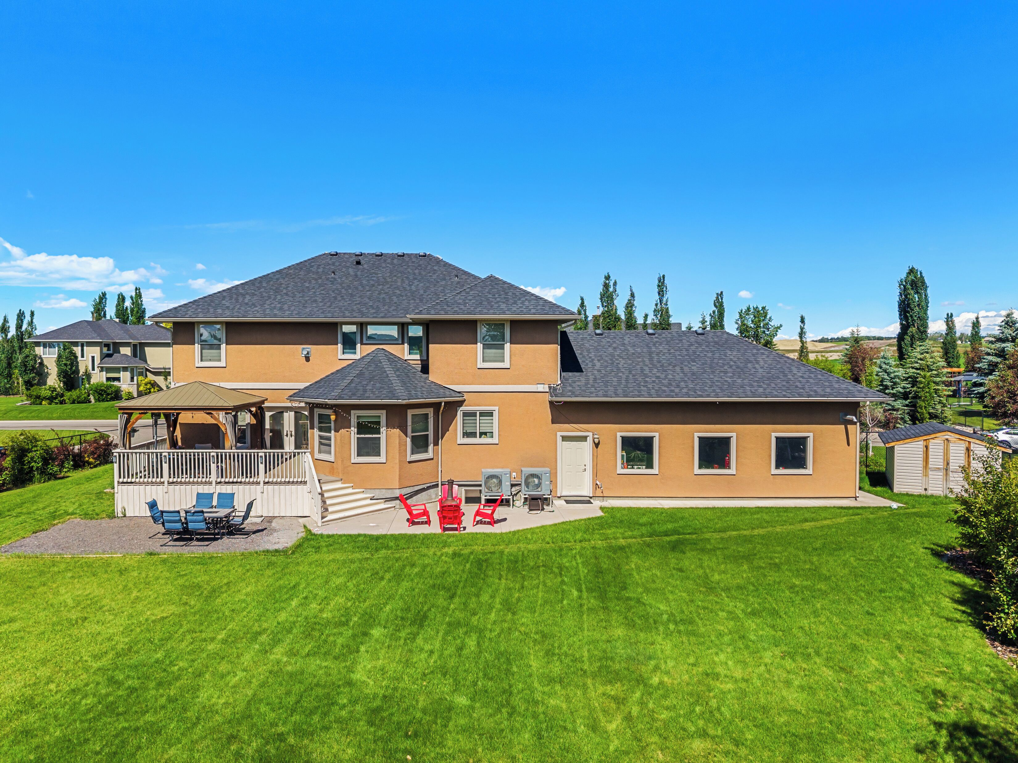 A two-story house with a covered patio and a well-maintained lawn.