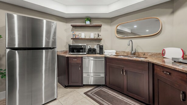 A modern kitchen with stainless steel appliances, wooden cabinets, and a built-in microwave. - Family Basement Retreat Near Rockies (Okotoks)