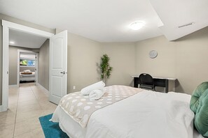 Hotellihuone, jossa on sänky, työpöytä, tuoli, viherkasvi ja kylpyhuone, joka näkyy avoimesta ovesta.
