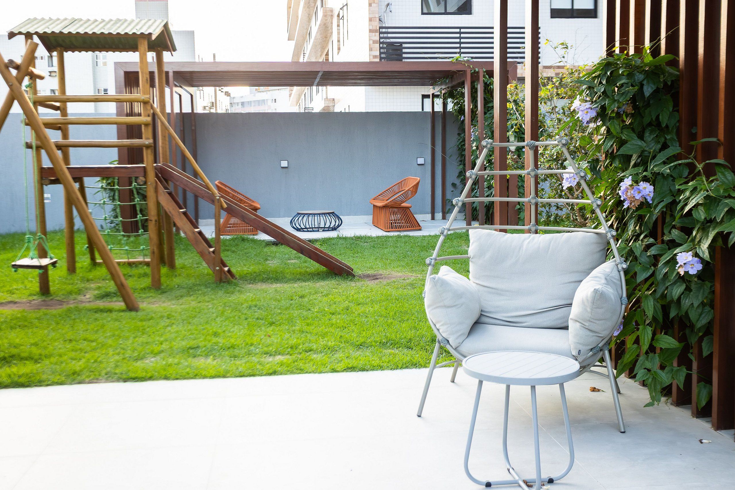 A patio with a swing set, a hanging chair, and a small table.