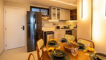 Uma cozinha moderna com forno embutido, geladeira e um espaço de jantar com mesa posta para dois.