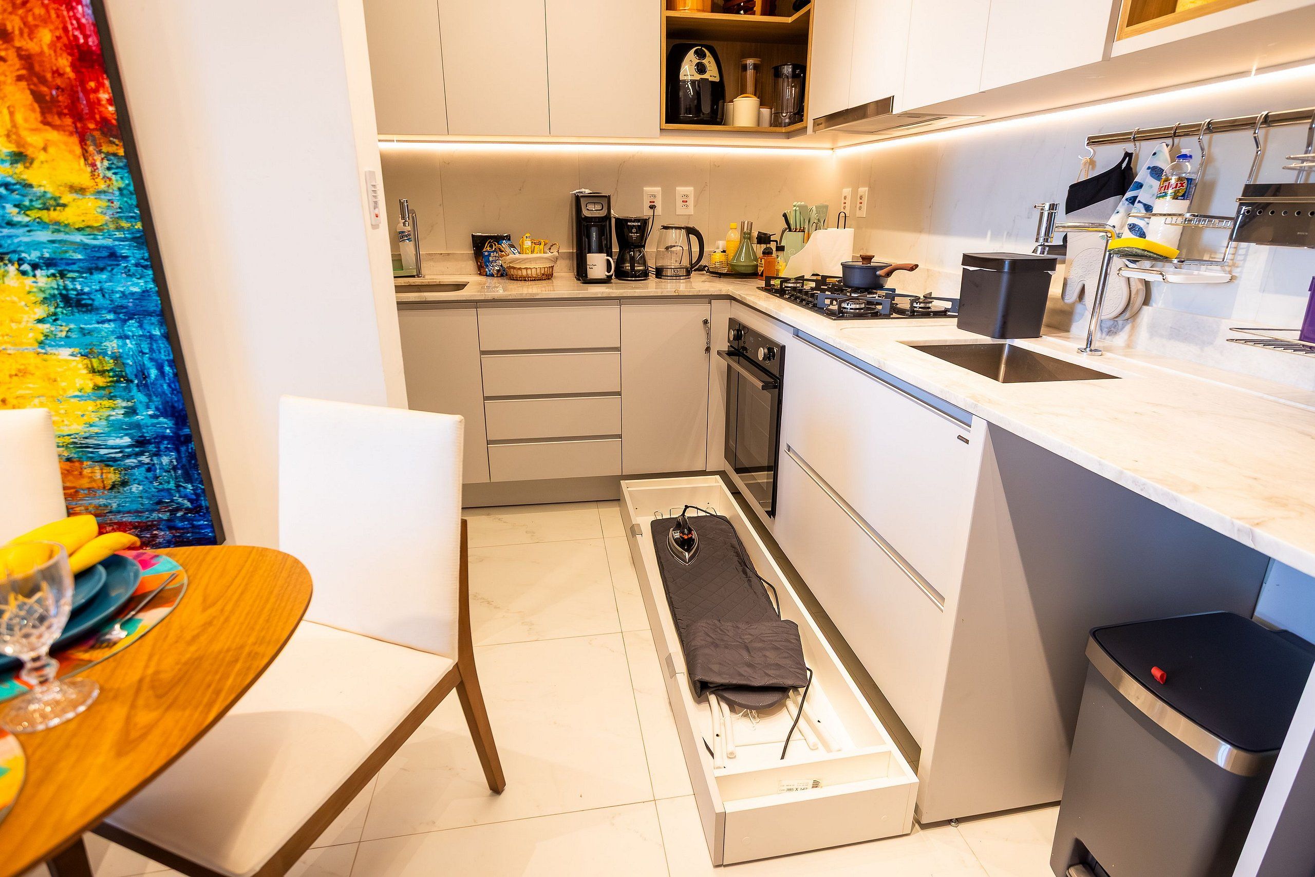 A compact kitchen with a built-in oven, a sink, and a coffee maker.