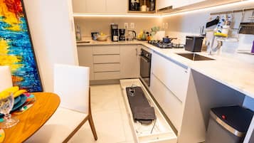 A compact kitchen with a built-in oven, a sink, and a coffee maker.