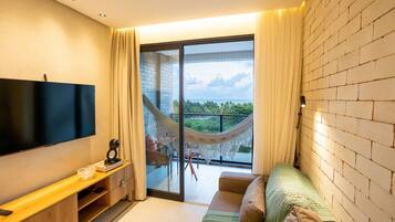 A modern living room with a flat-screen TV, a wooden console table, a sofa, and a balcony with a hammock.