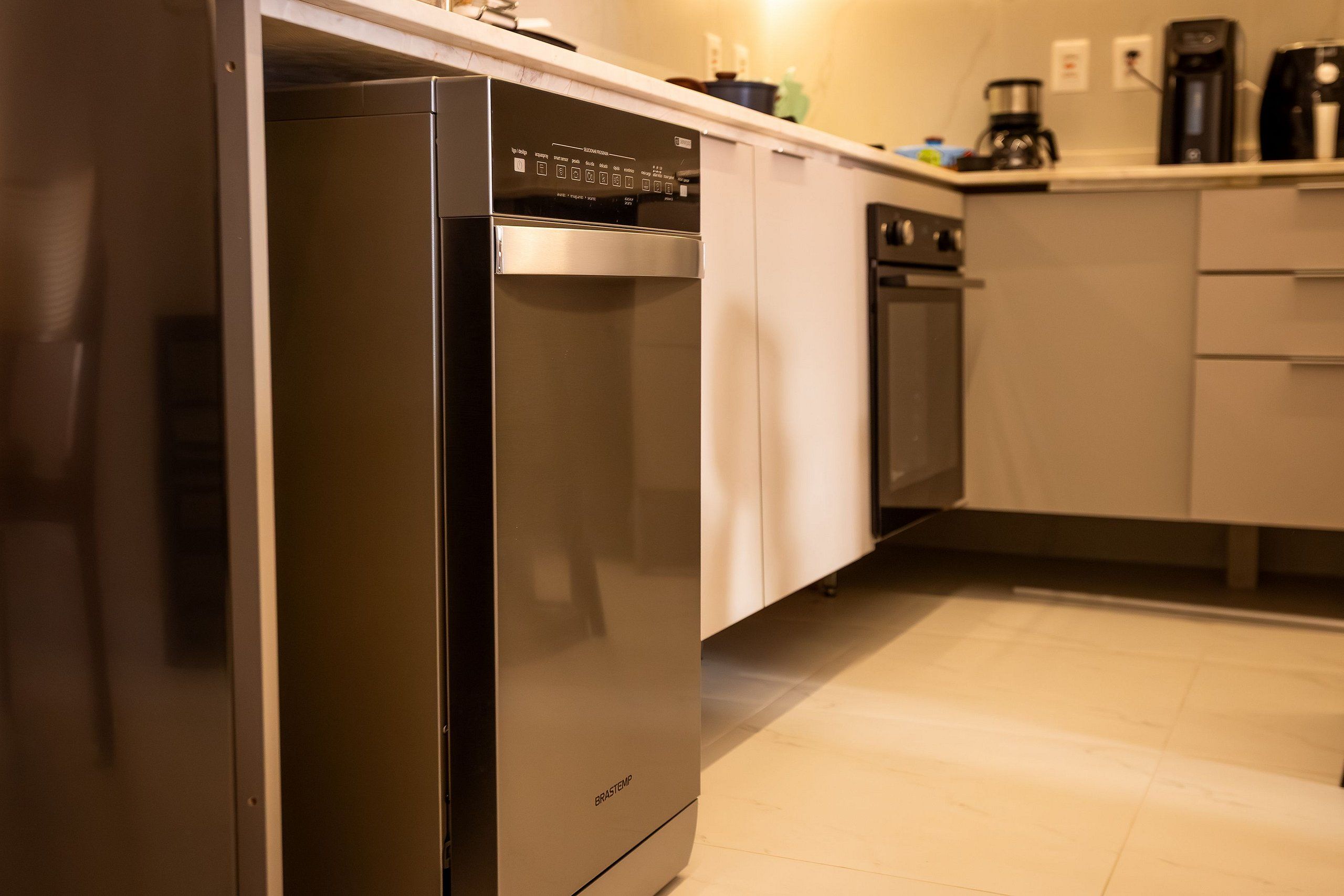 A kitchen with a stainless steel refrigerator, a dishwasher, and a coffee maker on the countertop.
