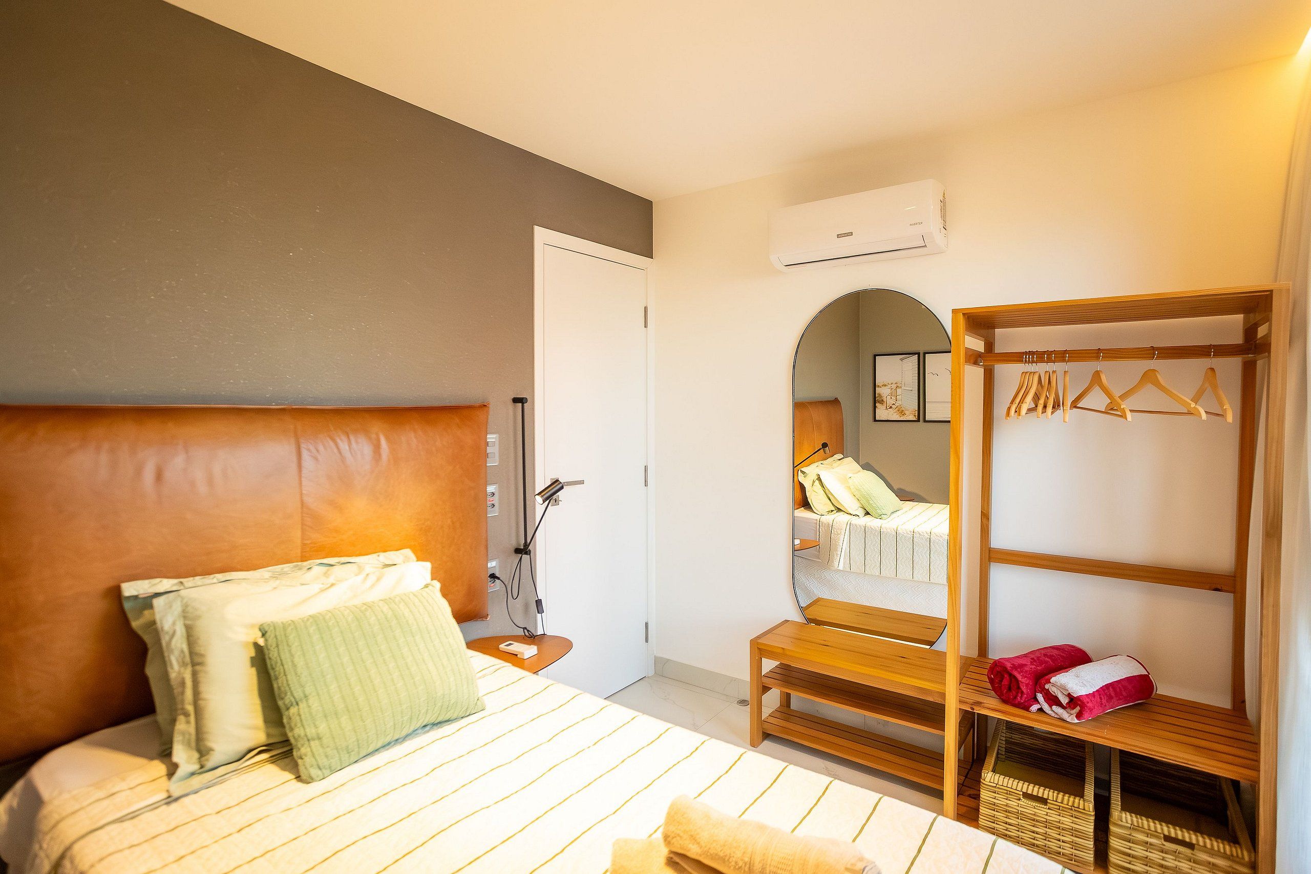 Un dormitorio con cama, mesita de noche, lámpara y armario con espejo.