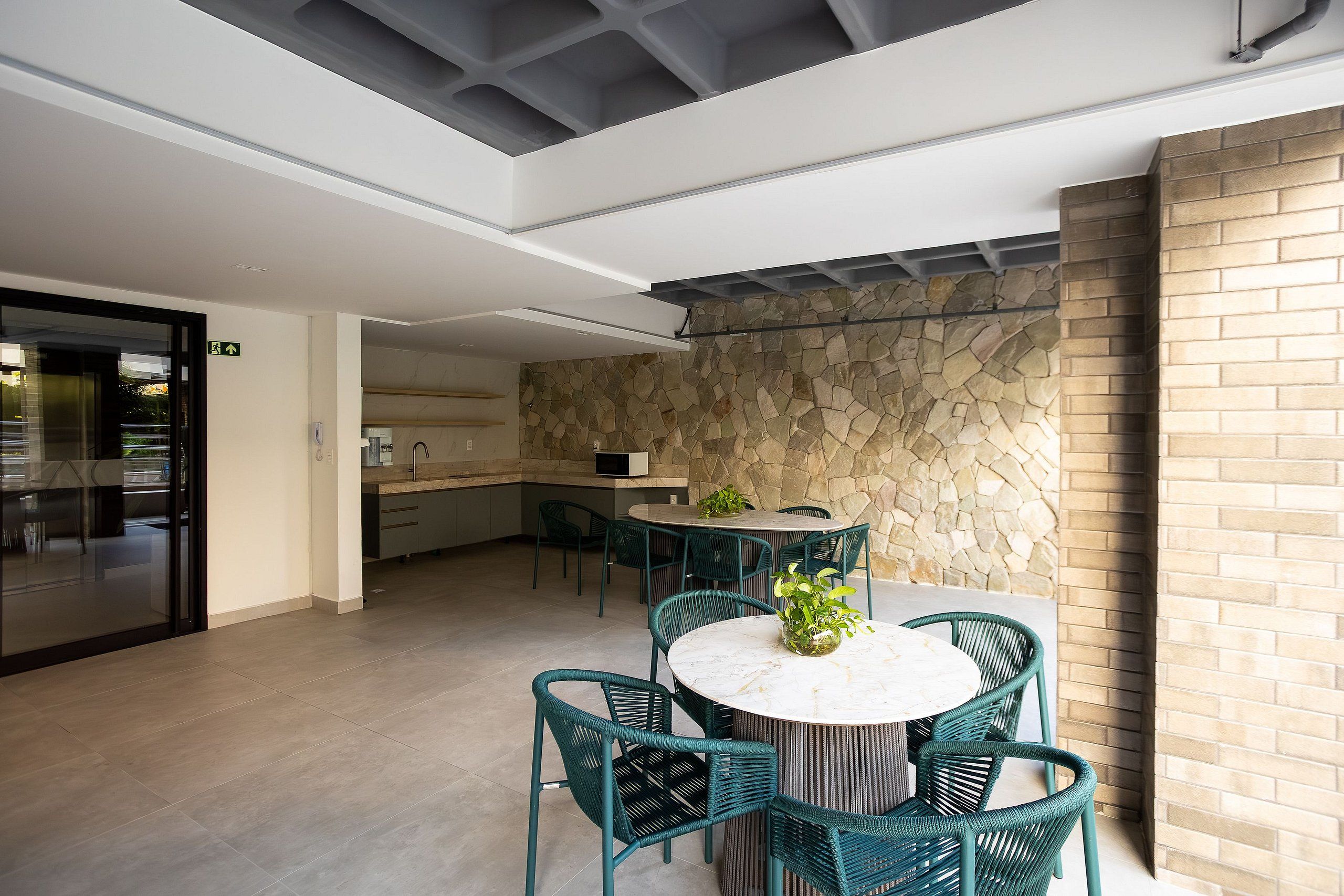 Una cocina moderna con protector de piedra, una mesa de comedor redonda con sillas y un techo con vigas a la vista.
