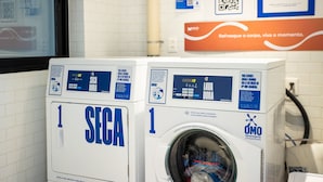 Pesulassa, jonka seinät on laatoitettu, on kaksi etuaukosta täytettävää pesukonetta. Toisessa on merkintä »SEGA» ja toisessa »OMO». Seinällä niiden yläpuolella on juliste.
