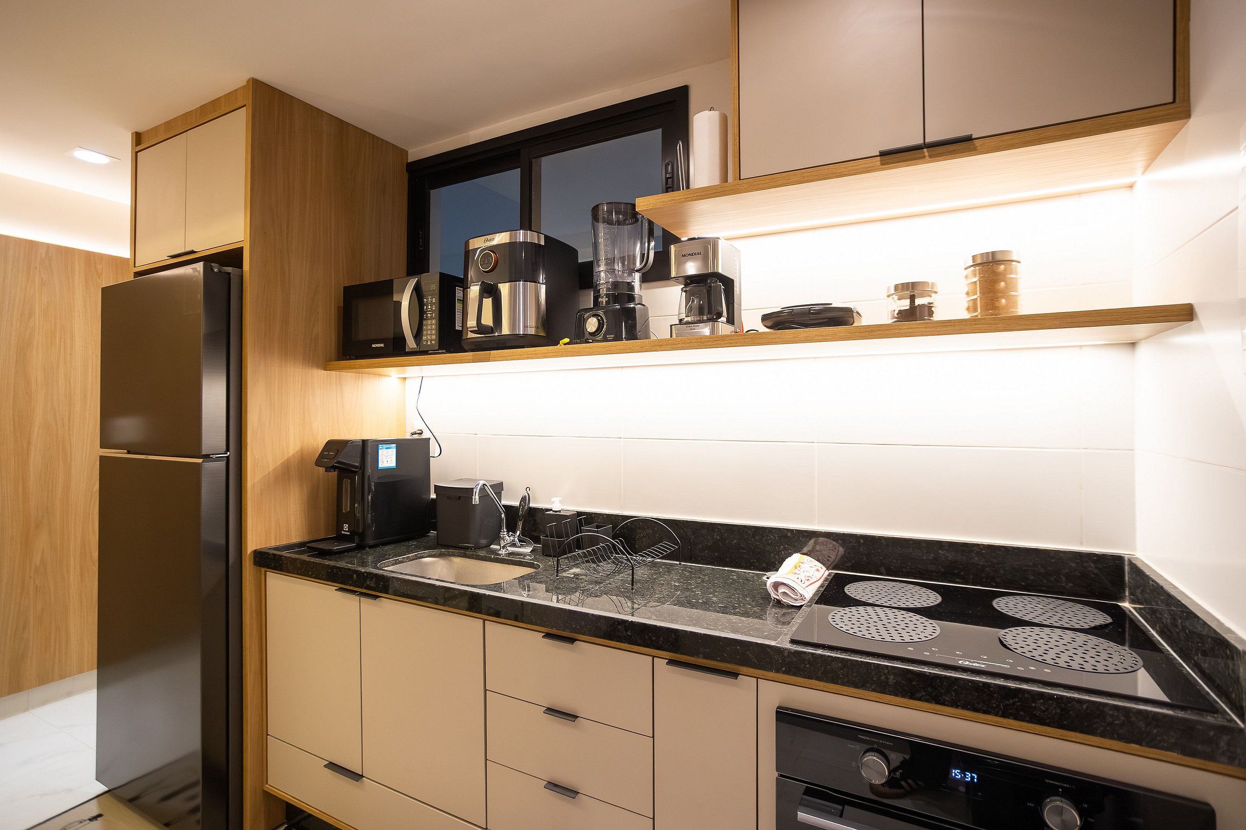 Una cocina moderna con refrigerador empotrado, microondas, cafetera y estufa.