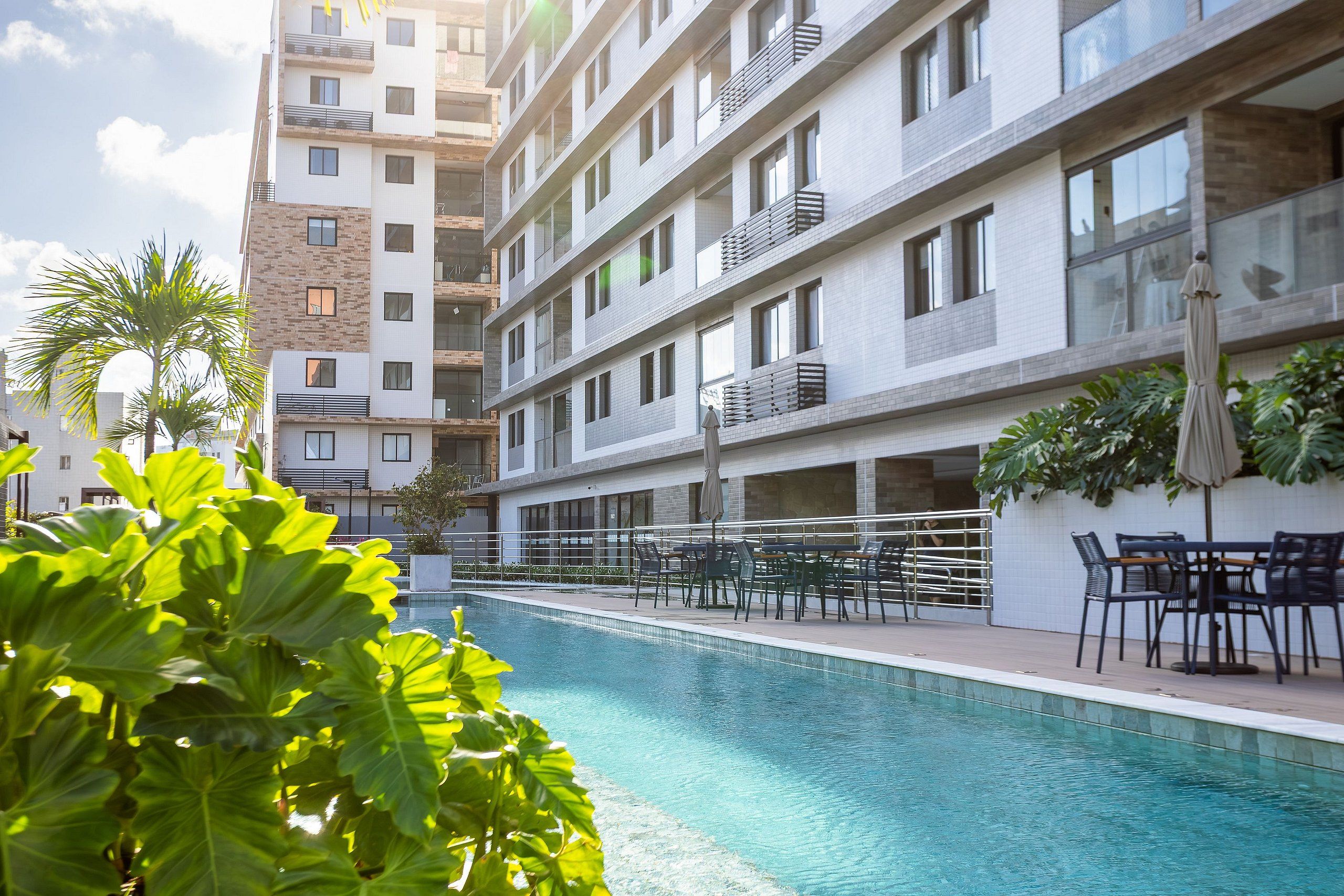 Hotel moderno com piscina, área de estar externa e vista dos edifícios ao redor.