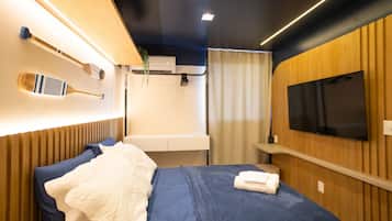 A modern bedroom with a bed, a mounted television, and a wall-mounted air conditioning unit.