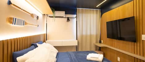 A modern bedroom with a bed, a mounted television, and a wall-mounted air conditioning unit.