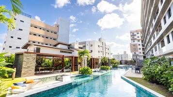 Un hôtel moderne doté d’une piscine, d’un espace extérieur aménagé et d’une végétation luxuriante.