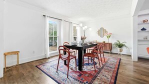 Un coin repas avec une table noire, des chaises rouges, un tapis à motifs et une vue dégagée grâce à de grandes fenêtres.