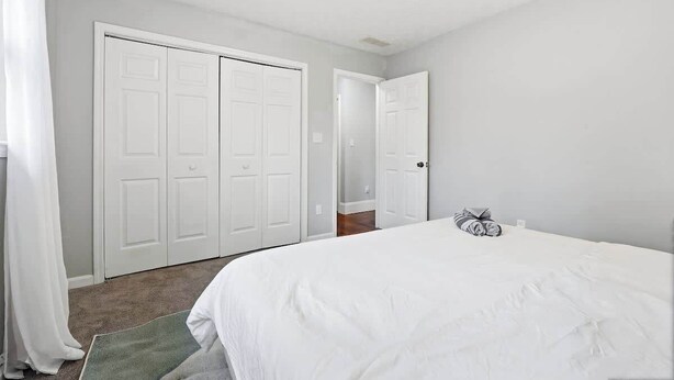 Une chambre à coucher comprenant un lit, une armoire et une porte donnant sur une autre pièce.