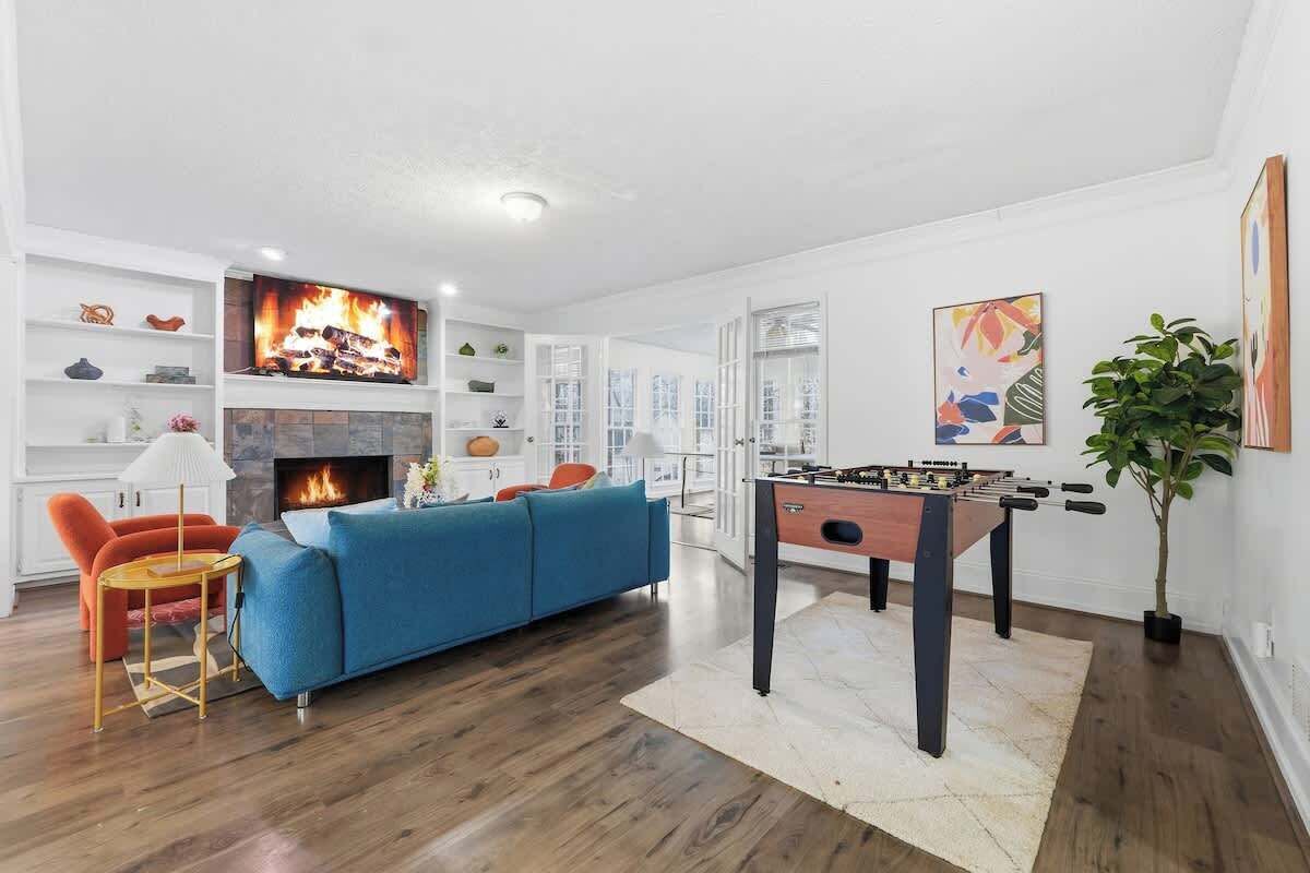 Una sala moderna con chimenea, un sofá azul, una mesa de futbolín y un televisor.