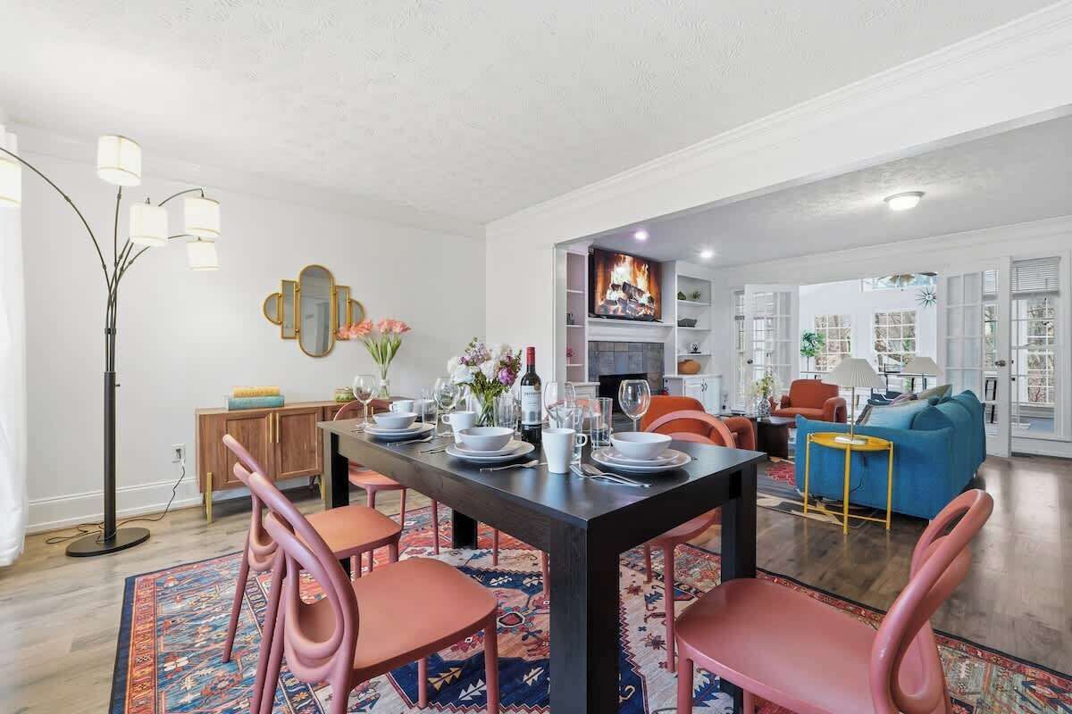 Un coin repas avec une table en bois foncé, des chaises roses et un tapis à motifs.