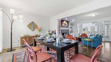 Un coin repas avec une table en bois foncé, des chaises roses et un tapis à motifs.