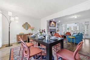 Un comedor con una mesa de madera oscura, sillas rosa y un tapete estampado.