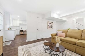 A modern living room with a sofa, coffee table, and a rug. - Windsor House | All-King| Sun-Filled Game Room (Lawrenceville)