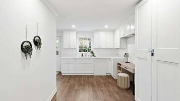 Une cuisine moderne avec des meubles blancs, un plancher en bois et une fenêtre offrant une belle vue.