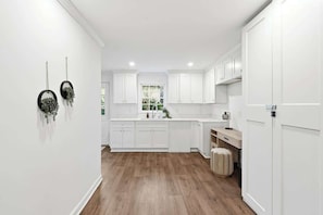 Una cocina moderna con armarios blancos, piso de madera y una ventana con vistas.