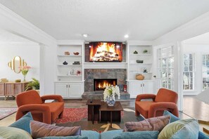 Una sala de estar con chimenea, dos sillones, un sofá y una mesa de centro.