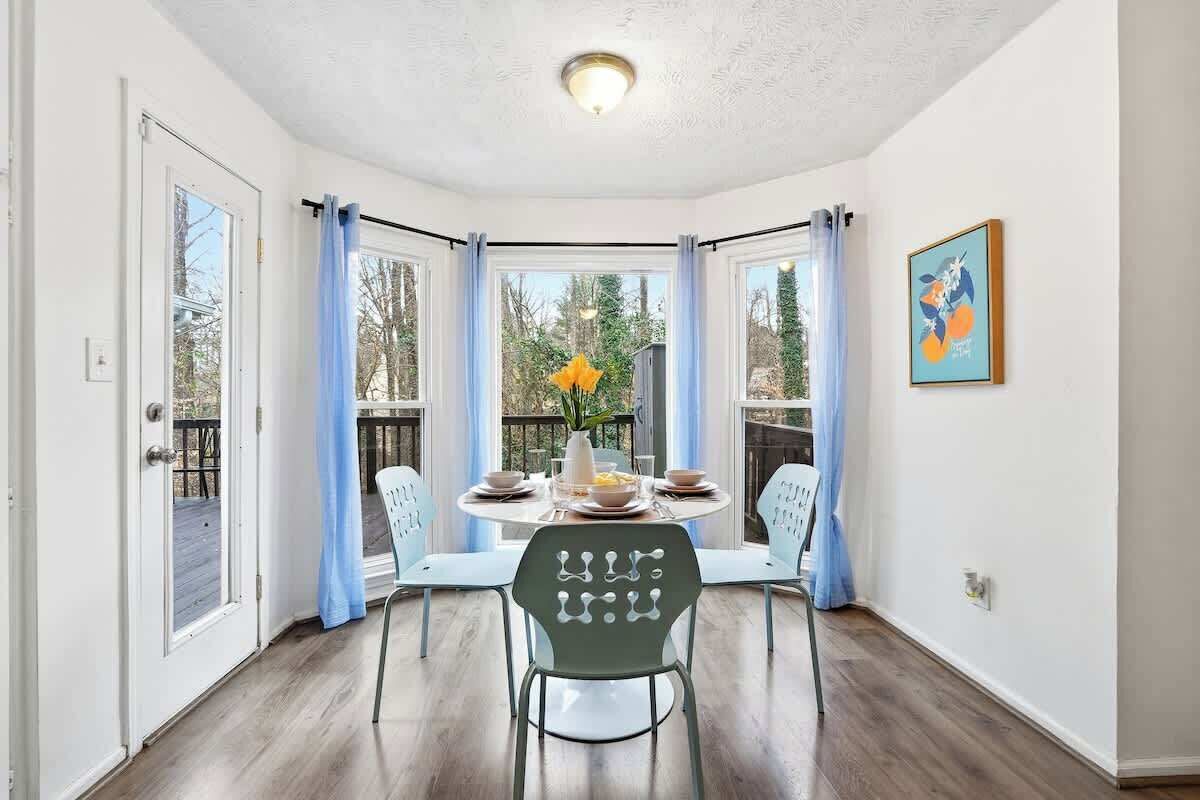 Un espace repas comprenant une table ronde, des chaises et une vue sur l’extérieur.
