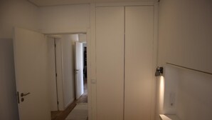 Et soveværelse med seng, garderobeskab, natbord og sengebord.
