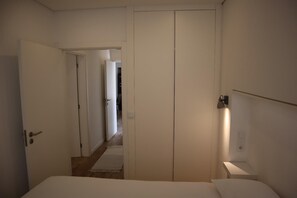 A bedroom with a bed, a wardrobe, a bedside table, and a nightstand. - Montebelo I (Porto)