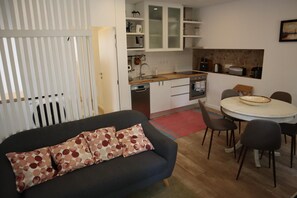 Ein gemütlicher, kleiner Wohnbereich mit Sofa, Esstisch und Küchenzeile.