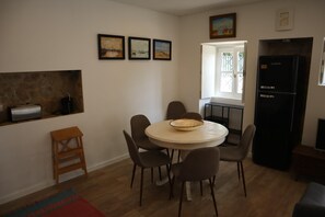 A dining area with a round table, chairs, a bowl, a refrigerator, and artwork on the wall. - Montebelo I (Porto)