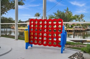 Een rode en blauwe speelconstructie met ronde gaten, nabij een waterpartij en palmbomen.