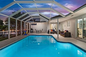 Ein Schwimmbecken mit überdachter Terrasse, Gartenmöbeln und Blick zum Himmel.