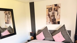 Un dormitorio con una cama grande, dos mesitas de noche, una lámpara y obras de arte en las paredes.