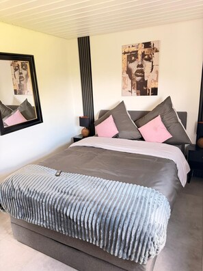 A bedroom with a large bed, two nightstands, a lamp, and artwork on the walls. - Modernly furnished & fully renovated Holiday apartment (Owingen)