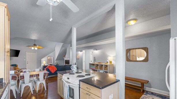 Une cuisine moderne dotée d’un îlot central, de meubles blancs et d’un coin repas avec des chaises.