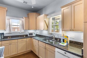 A kitchen with wooden cabinets, a microwave, a sink, and a dishwasher. - 3BR Coastal Retreat | 10 Min to Beaches (Pensacola)